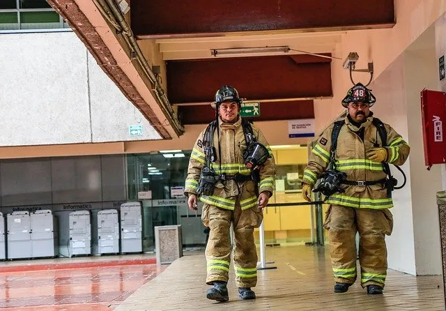 Two firefighters in turnout gear inside a building