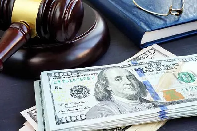 A gavel resting beside a stack of hundred-dollar bills