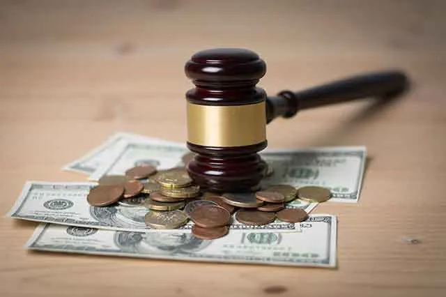 A gavel resting on banknotes and coins