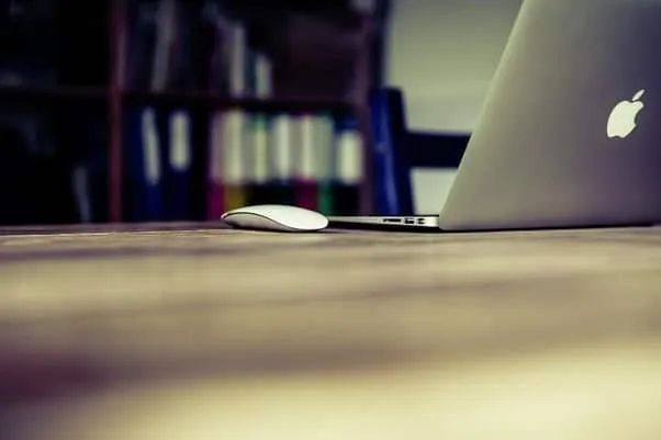 A laptop open on a desk in front of a bookshelf