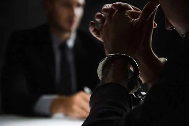 Two men talking across a table in a dimly lit office
