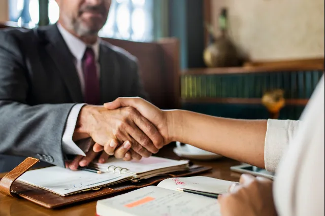 An attorney shaking hands with a client across a desk