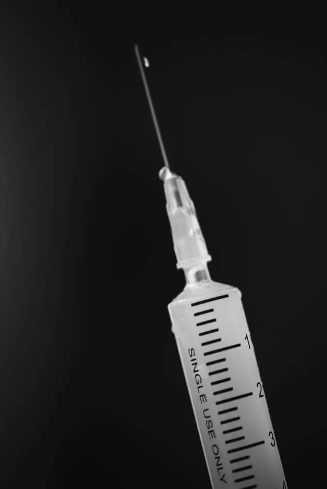 A hypodermic syringe on a black background