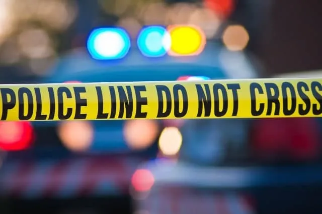 Police line do not cross tape in front of patrol car lights
