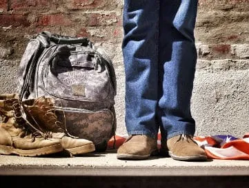 A soldier's rucksack and boots beside a pair of civilian shoes