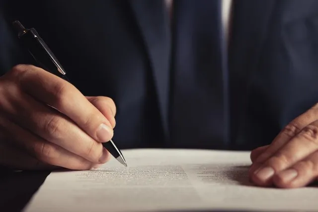 A person signing a document at a desk