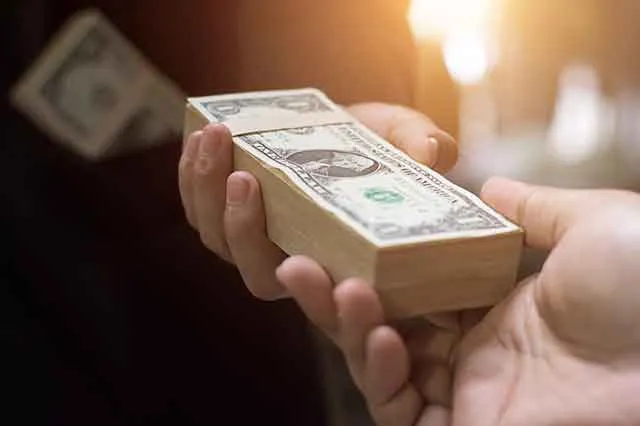One hand passing a stack of cash to another