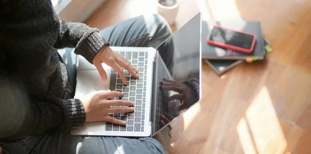 Hands typing on a laptop at a table