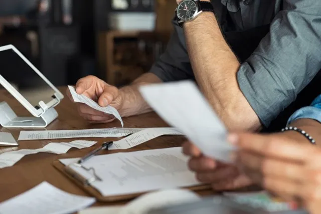 A man working through receipts and paperwork at a desk