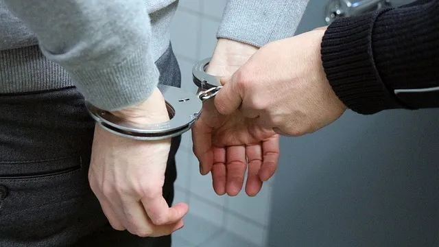 A person's hands being placed in handcuffs
