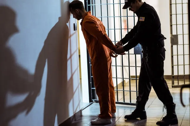 A corrections officer escorting an inmate in a jail corridor