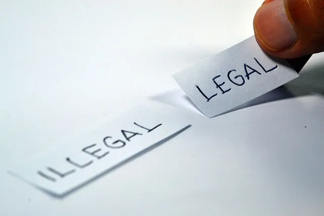 A sheet of paper torn between the words legal and illegal