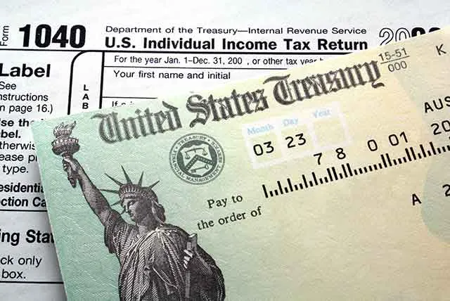 A US Treasury check resting on a Form 1040 tax return