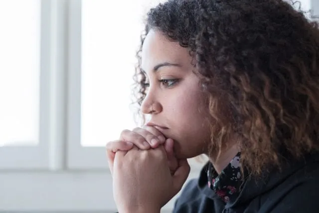 A woman sitting alone with her hands clasped