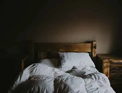An unmade bed in a dimly lit room