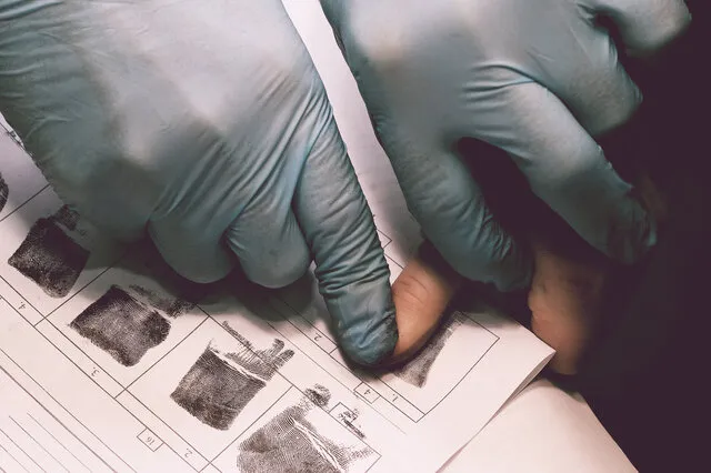 Gloved hands recording fingerprints on a card