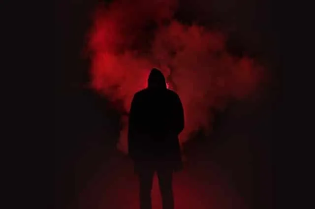A hooded figure standing in red smoke