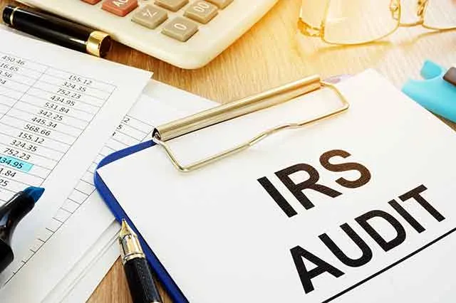 A clipboard headed IRS Audit beside a calculator and pen