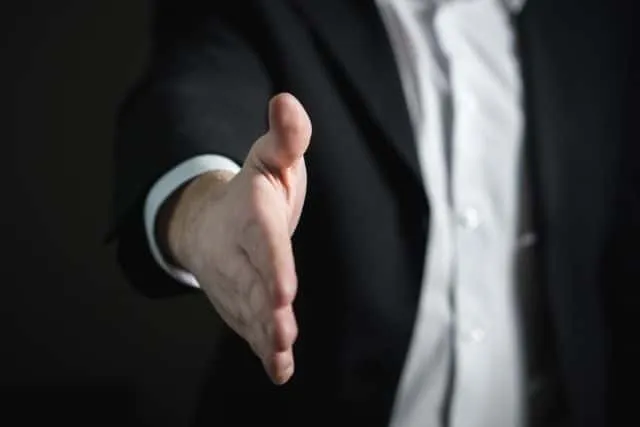 A man in a suit extending his hand to shake